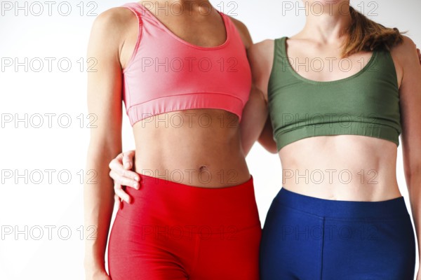 Two joyful happy women in sportive pink hoodie taking break after yoga classes or workout, standing