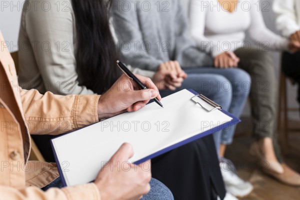 Man writing clipboard group therapy session