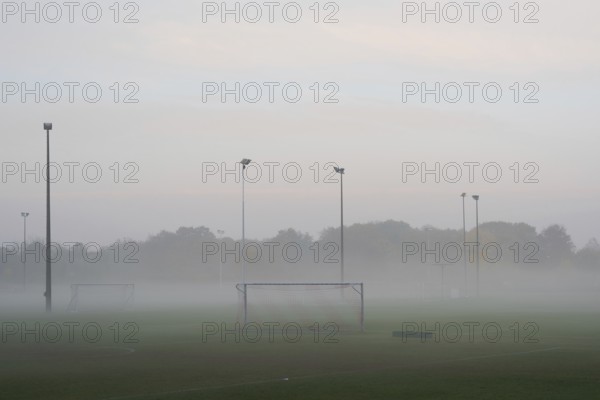 Empty and deserted soccer field in suburban area with goals and flood light poles on grey overcast