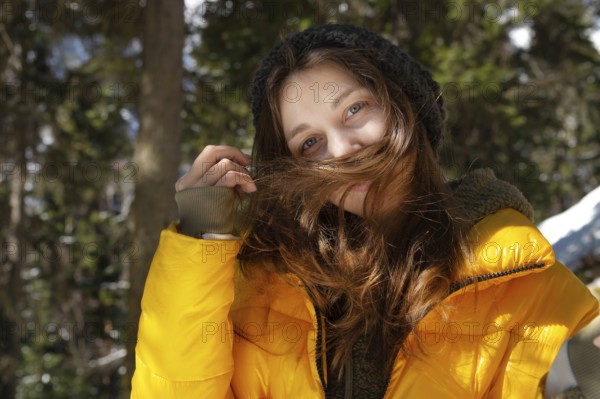 Happy young caucasian woman in a winter down jacket hat and mittens with happiness rejoices