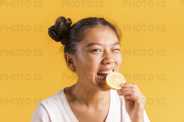 Woman bites slice sour lemon