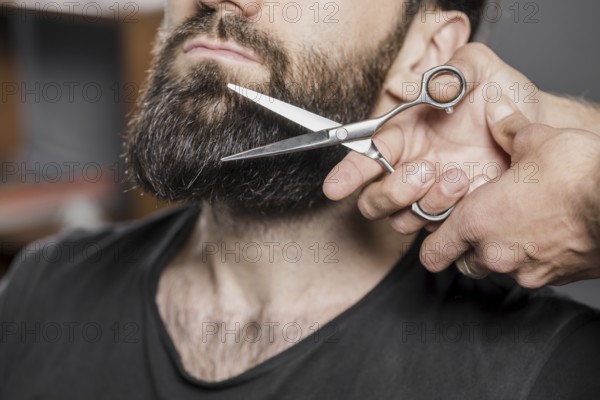 Hairstylist s hand cutting man s beard with scissors. Resolution and high quality beautiful photo
