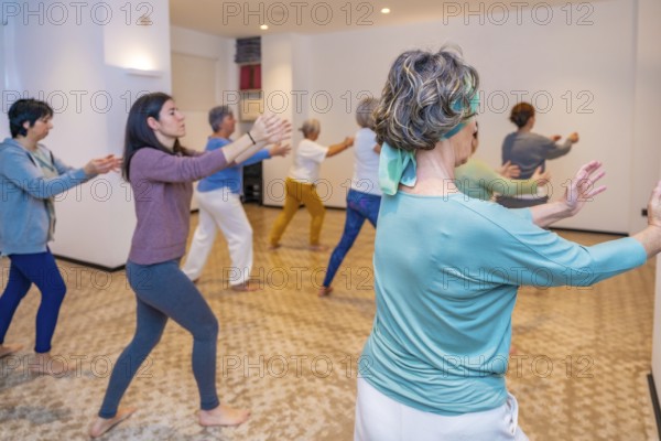 Group of women simulating waves in a choreographed Qi Gong exercise in a classroom