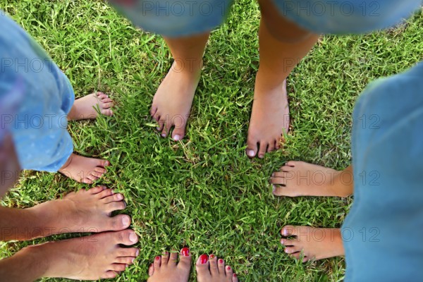 Happy young family spending time outdoor on a summer day. Feet on the grass. Top view