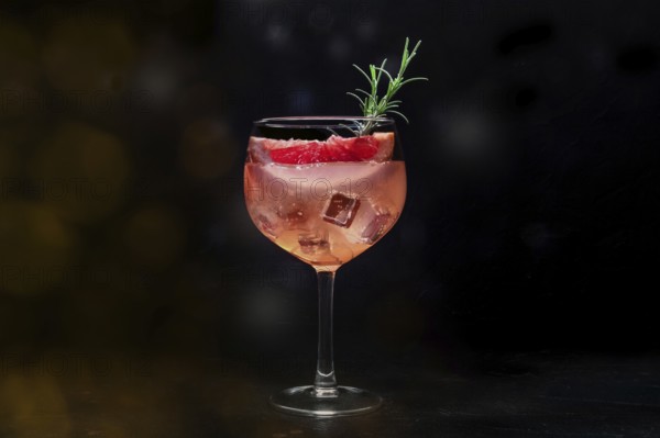 Fancy cocktail with fresh fruit. Gin and tonic drink with ice at a party, on a black background.