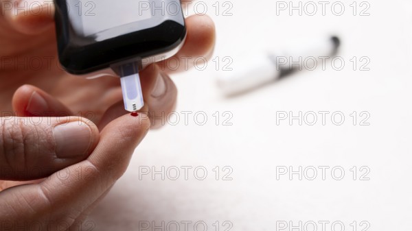 Pierced caucasian finger ready to measure glucose level by glucose meter closeup view with