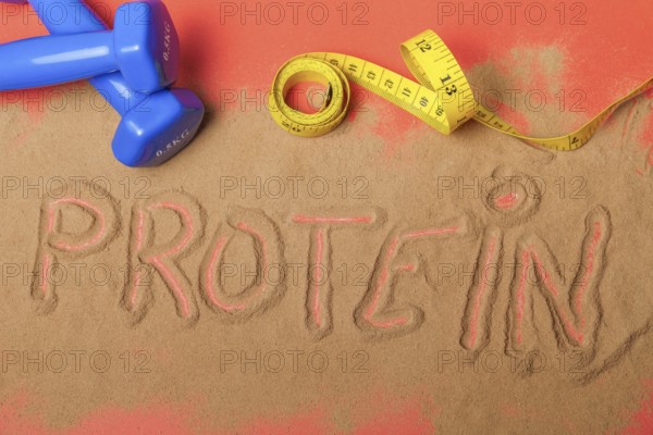Word protein written on protein powder on red background, with dumbbells and measuring tape