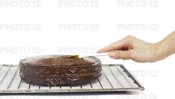 Pastry chef making final touches to a sacher chocolate cake with icing