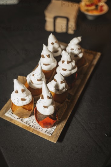 Halloween food and sweets in the shape of pumpkins at a party, chocolate ghost cupcakes