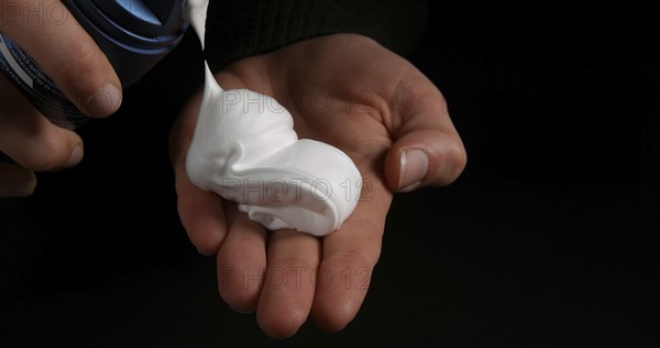 Hand of Woman and shaving foam against Black Background