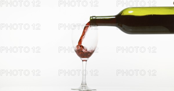 Red Wine being poured into Glass, against White Background