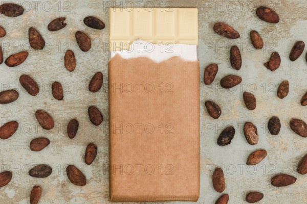 Scattered cocoa beans with white chocolate bar grunge background