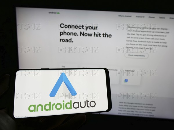 Stuttgart, Germany, 03-14-2023: Person holding mobile phone with logo of mobile app Android Auto