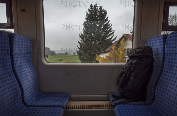 German train interior with a rucksack on the seats and a bavarian landscape view on the window