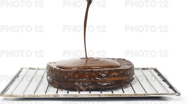 Closeup of chocolate icing pouring over Sacher torte towards white