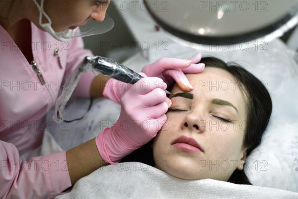 The master does the tattoo on the eyebrows to the girl