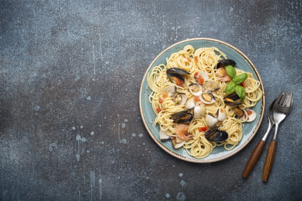 Italian seafood pasta spaghetti with mussels, shrimps, clams in tomato sauce with green basil on