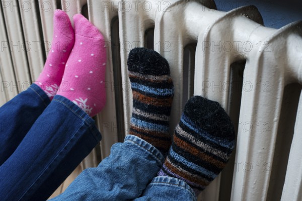 Couple warming up their feet on central heating radiator