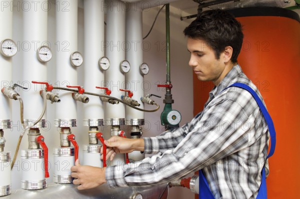 Young heating technician maintains a heating system, Austria, Europe
