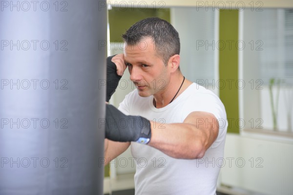 Boxers trained on a punching bag. Man trains on a punching bag