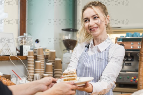 Smiling female baker serving pastry cake customer