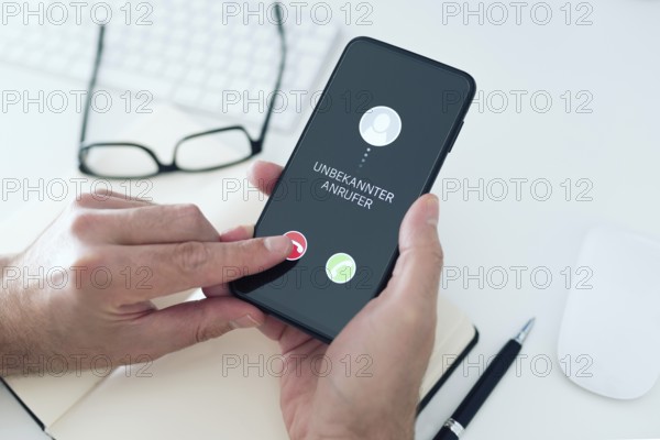 close-up view of person rejecting call from unknown number with text UNBEKANNTER ANRUFER, German
