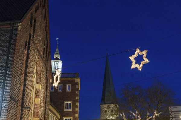 Night landscape of the town with Christmas stars and illuminated church tower against a dark sky,