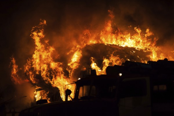 Arson or nature disaster, burning fire flame on wooden house roof