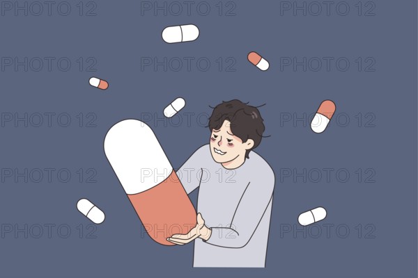 Unhappy stressed man suffer from drug addiction hold huge pill. Upset unhealthy guy struggle with
