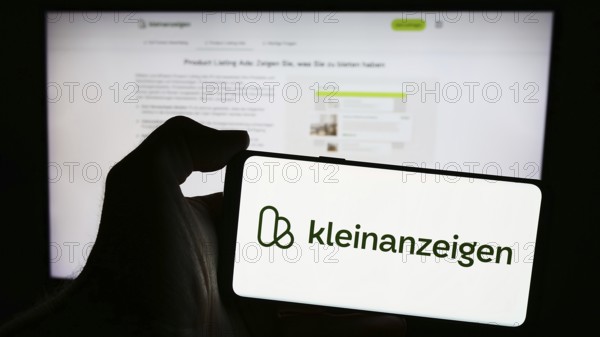 Stuttgart, Germany, 04-13-2024: Person holding mobile phone with logo of German classifieds