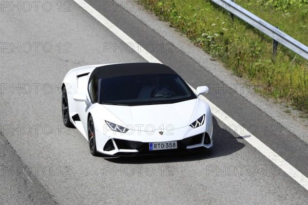 White Lamborghini Huracán LP 580-2 Spyder supercar at speed on motorway E18, elevated view. Salo,