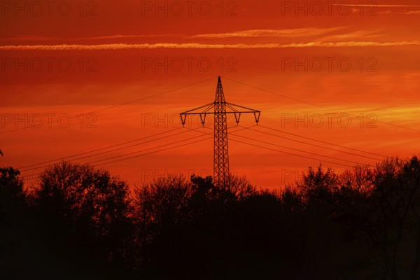 High-voltage pylon, electricity pylon with high-voltage lines at sunset, Bad Wünnenberg, North