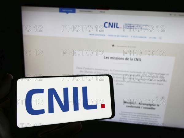 Stuttgart, Germany, 11-21-2023: Person holding smartphone with logo of Commission Nationale de