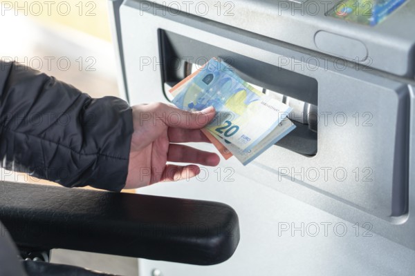 Close up photo of man taking cash, euros from ATM