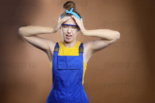 Young attractive caucasian woman repairman construction worker in the uniform of a handyman holds