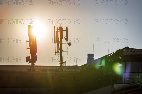 Silhouette of communication or cell tower on the rooftop of a building, evening sunshine