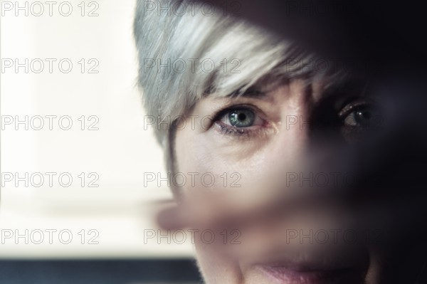 A woman looks through the fingers of her hand