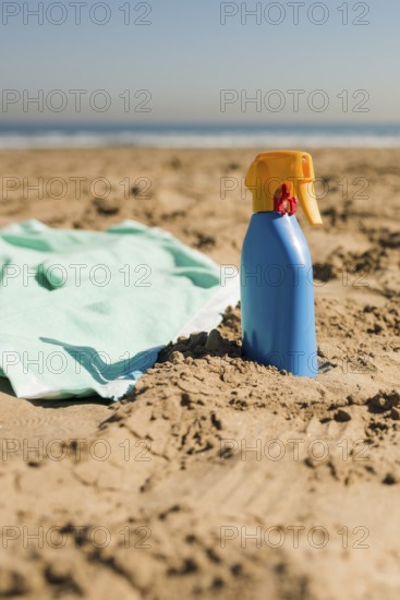 Close up blanket sunscreen cream blue bottle sand beach