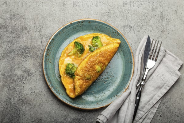 Healthy vegetarian egg omelette with green broccoli folded in half served on plate with fork and