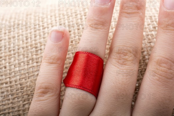 Red string tied around ring finger of the hand