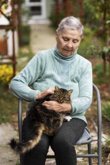 Older woman sitting chair petting cat