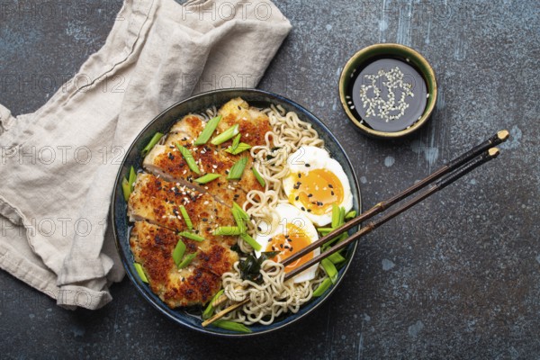 Asian noodles ramen soup with deep fried panko chicken fillet and boiled eggs in ceramic bowl with