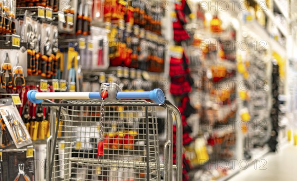 A shopping cart by a store shelf in a hardware store