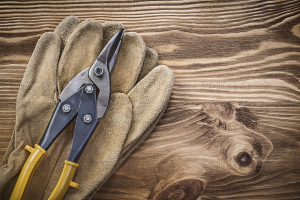 Leather protective gloves Pewter scissors on wooden board Construction concept