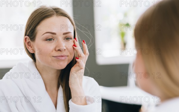 Blonde girl applying cream her face