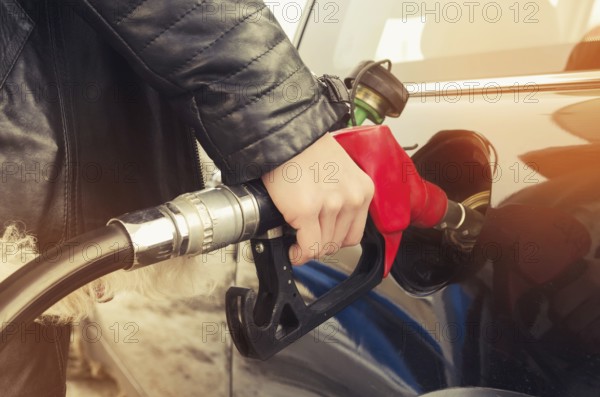 Hipster woman in sunglasses fills gasoline car