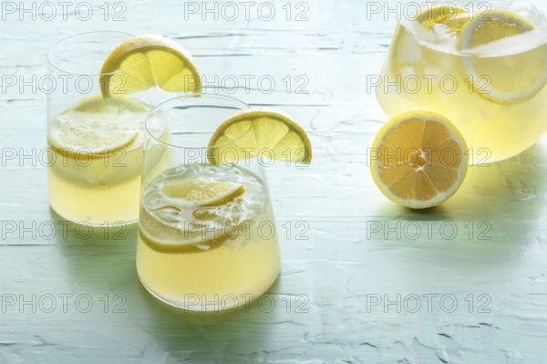 Lemonade. Lemon water drink with ice. Two glasses and a pitcher on a blue background. Detox