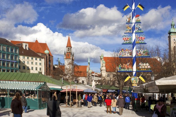 Busy food market Viktualienmarkt in February, winter, may pole in the middle ground, tower of old
