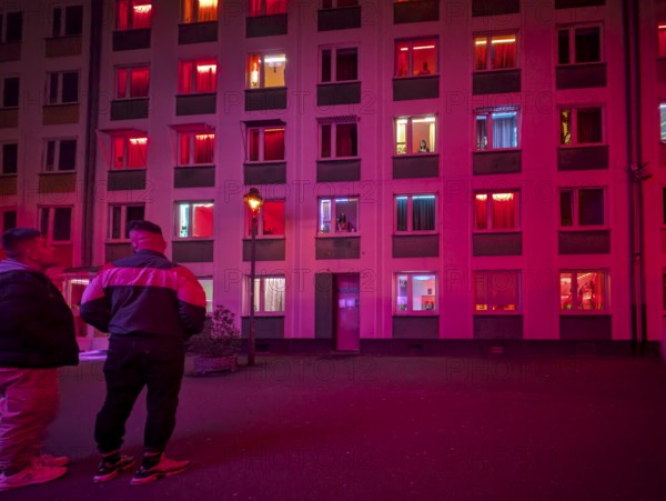 Laufhaus, clients in front of the facade of a red-lit brothel with prostitutes in the windows,