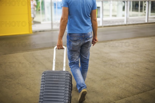 Young man with suitcase at airport or station with suitcase. Close up